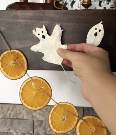 Garland made from sliced oranges alongside leaves painted to resemble white ghosts