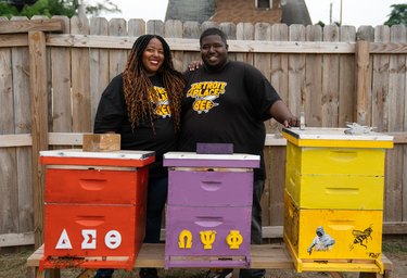 The founders of Detroit Hives standing in front of colorful beehives
