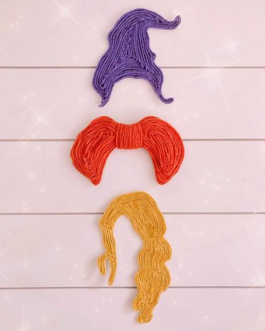 Wall decor made from hot glue and yarn to resemble the hairstyles of the Sanderson sisters from Hocus Pocus