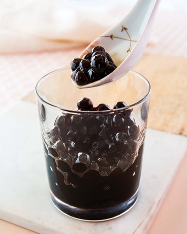 A close-up of boba in a glass with a spoon scooping out some Boba bubbles