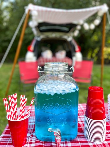 cinema soda in large glass drink dispenser with cups and straws