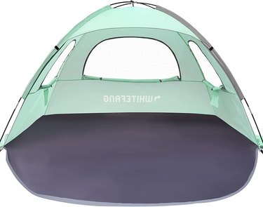 Mint green tent that's enclosed on three sides with large mesh windows and a fiberglass rod frame.