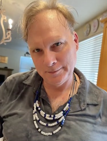 Caucasian man wearing four beaded necklaces