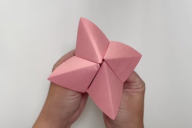 A pink paper cootie catcher, also known as a paper fortune teller