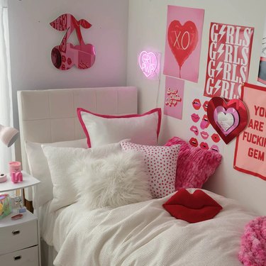 Acrylic cherry wall art behind a dorm room bed. It has a mirror-like finish and is pictured here in hot pink, surrounded by coordinating posters.