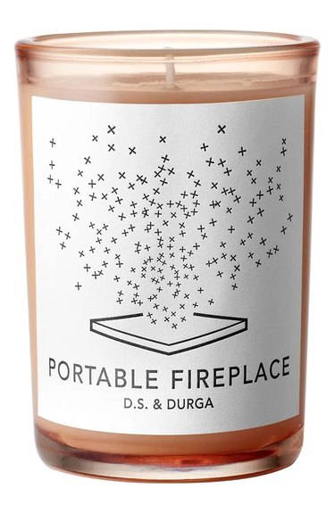 D.S. & Durga Portable Fireplace candle in a rose-colored glass vessel. It's labeled "Portable Fireplace" with the brand name and a geometric design on it.