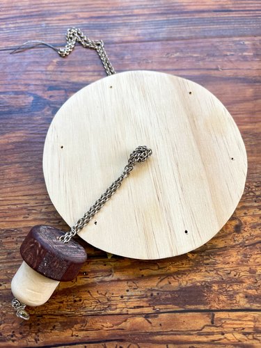 thread the chain through the center hole in the wooden disc