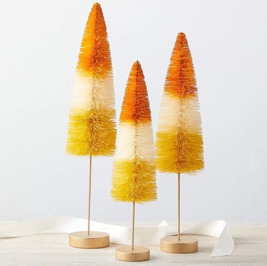 Three Fall Bottle Brush Trees from Amazon that resemble candy corn in colors yellow, white, and orange.