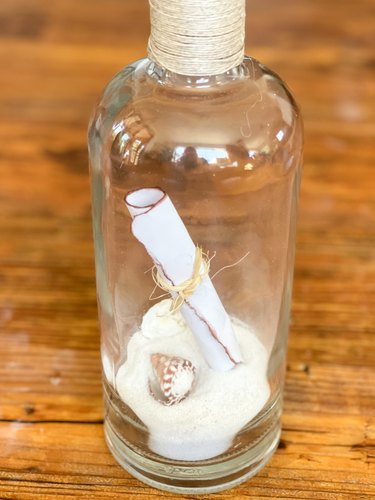note, shells and white sand inside bottle