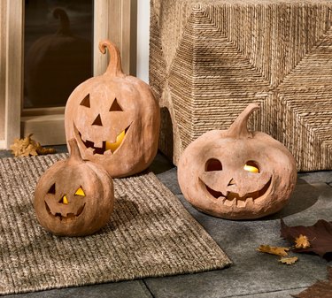 Handmade Terracotta Jack O' Lanterns from Pottery Barn with LED candles inside of them. The faces are happy and smiling.