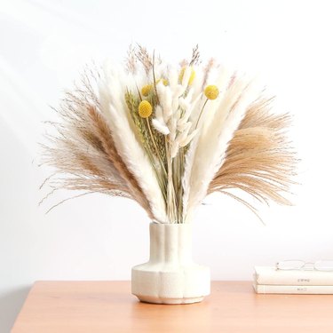 Natural Dried Pampas Grass Bouquet from Amazon in a ceramic vase on a wooden table. The pampas grass is mixed with some other dried stems.