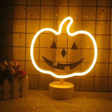 Pumpkin Neon Light from Amazon. The perimeter is neon light and the interior is clear plastic with a jack-'o-lantern face in black.