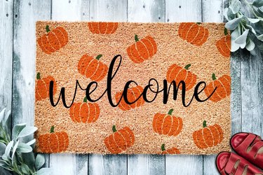 Coir doormat that says 'Welcome' in cursive surrounded by a cute pumpkin pattern.