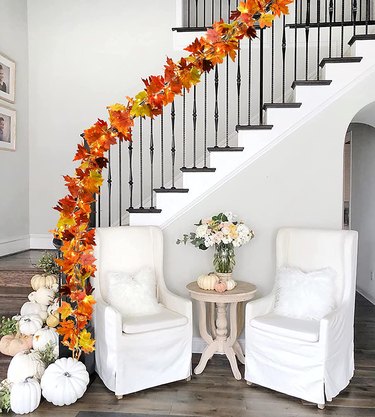 Fall Maple Leaf Garland from Amazon on a stair railing. The garland has LED twinkle lights and leaves on it.