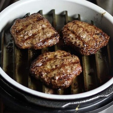 Burgers searing on the Grill Grates accessory inside a multi-cooker appliance