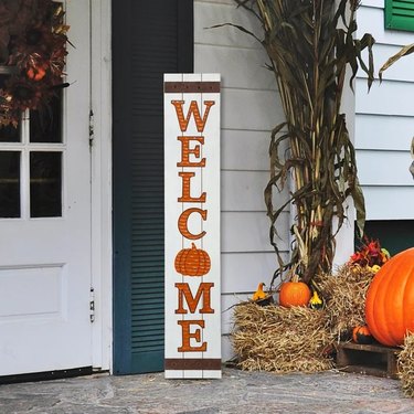 3D Pumpkin Welcome Fall Porch Sign from Wayfair. The sign is white with orange letters and a pumpkin as the 'O' in 'Welcome.'