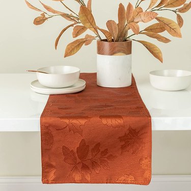Rust colored table runner with leaves on a table