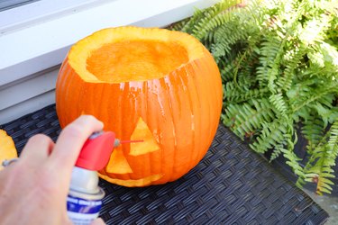 spraying a pumpkin with WD-40 to make it last longer