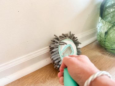 Using a dusting wand to clean baseboards