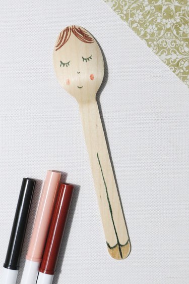 Drawing details on a spoon doll