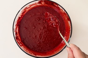 A mixture of red velvet cake mix and water in a clear bowl