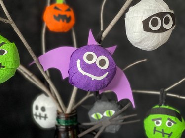 Purple bat, white mummy, orange pumpkin, black cat and green Frankenstein head made from tissue paper on a Halloween tree