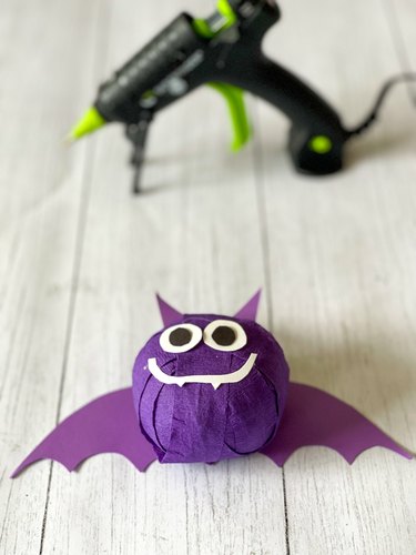 Use a hot glue gun to adhere paper shapes to Halloween Bat surprise ball