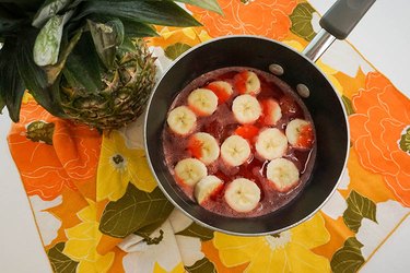Banana being added to strawberries, pineapple and Jell-O