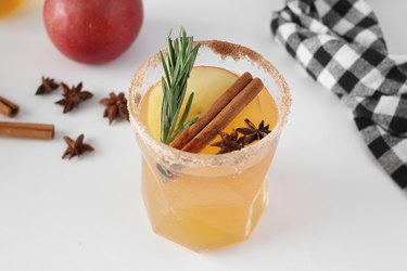 Sparkling apple cider with an apple slice, cinnamon stick, anise pods and rosemary sprig