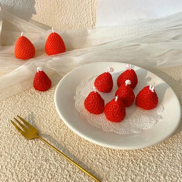 Plate of small red candles shaped like strawberries
