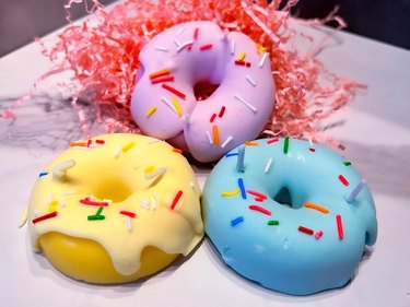 Three candles shaped like purple, yellow and blue donuts with sprinkles