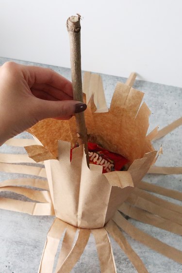 Fill witch's broom Halloween treat bag with candy and twig