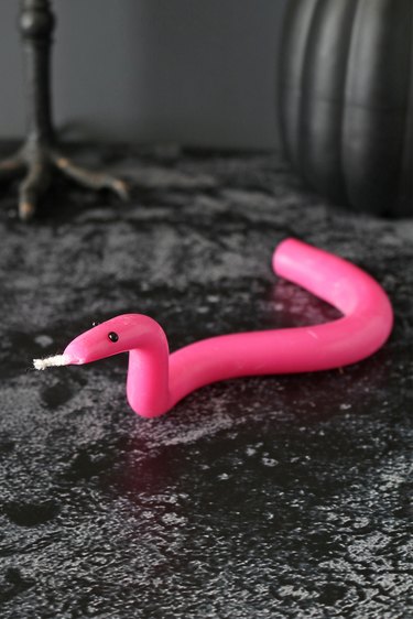 Pink wave snake candle on a black background