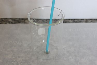 plastic straw with wick in glass beaker