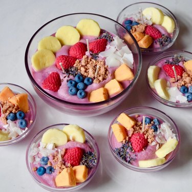 Candles in clear bowls shaped like pink smoothie bowls topped with fruit