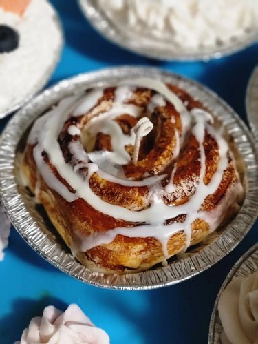 Candle shaped like a cinnamon bun with white icing