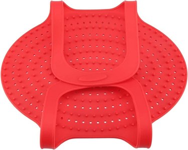A foldable perforated red silicone mat with two large loop handles
