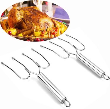 Two stainless steel four-pronged turkey forks pictured with a roasted turkey