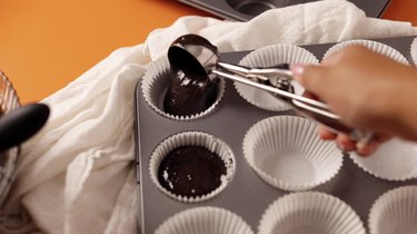 Scooping chocolate cake batter into cupcake liners