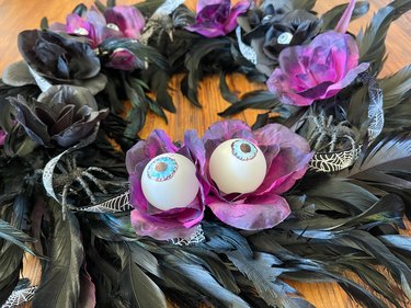 Black and purple wreath with faux flowers and plastic eyeballs