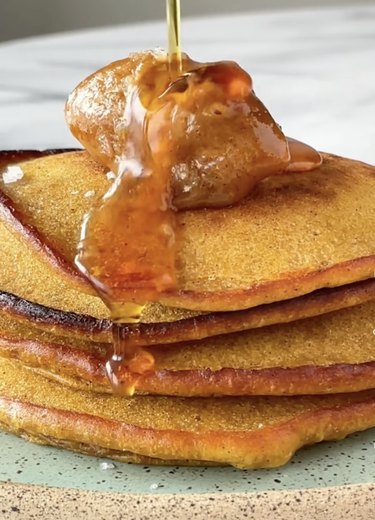 Stack of pumpkin pancakes topped with pumpkin butter and syrup