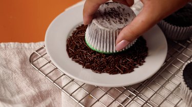 Dipping cupcake into chocolate sprinkles