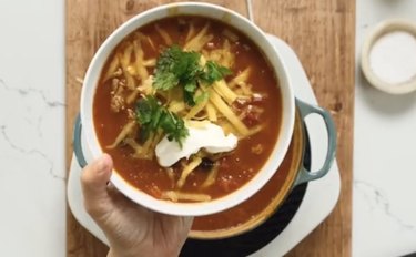 Chili in a small bowl topped with cheese and cilantro