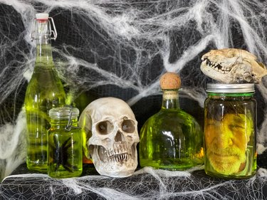 Glass jars filled with green liquid, faux spiders and a printed-out human face on laminated paper