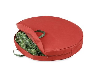 Red circular wreath bag with wreath inside and two top handles.