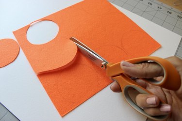 Scissors cutting out an orange felt circle