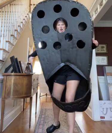 Woman in a black costume shaped like a Crocs shoe