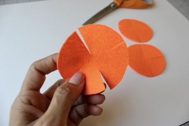 An orange felt circle with flower petal shapes cut into the side