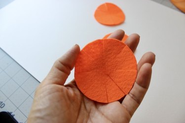 An orange felt circle with flower petal shapes cut into the side
