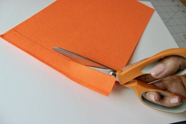 Scissors cutting a strip of orange felt